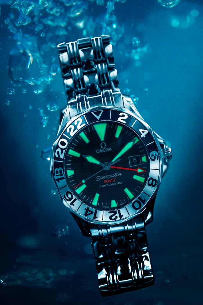 services-02 Close-up of an Omega Seamaster GMT wristwatch submerged underwater, showcasing luxury and waterproof features.