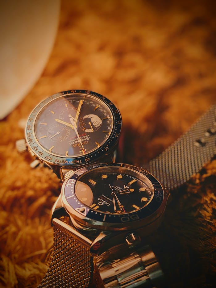 about-01 Close-up of two luxury watches with metal straps on a soft textured surface, showcasing timeless elegance.