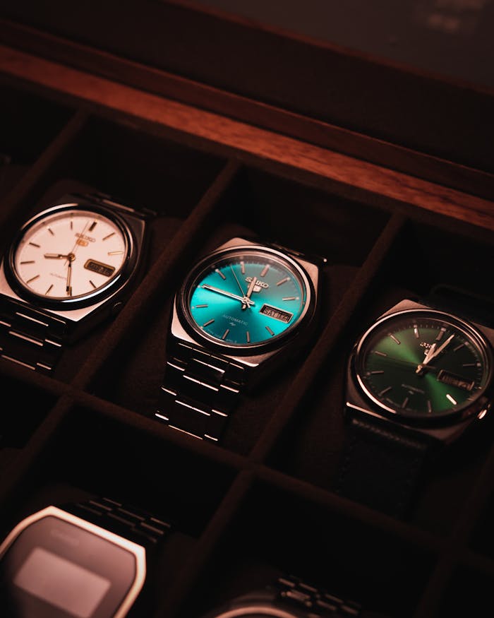 hero-img-01 Close-up of luxury wristwatches in a display case with vintage style lighting.